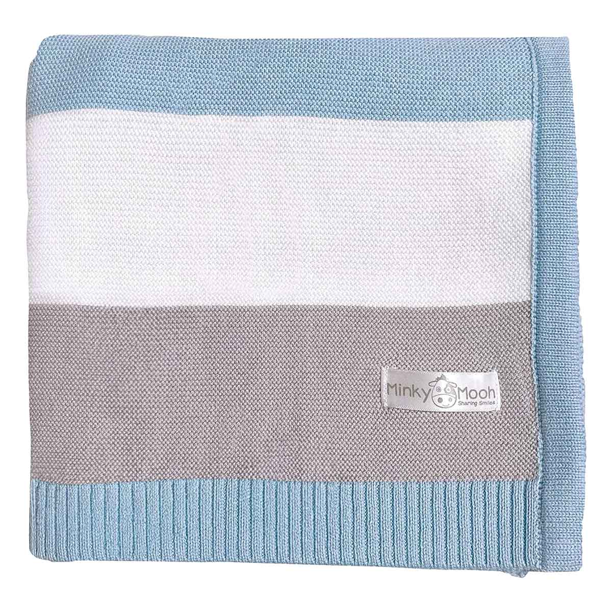 Flach liegende, blau-grau-weiße gestreifte Bio-Baumwolldecke mit Minky Mooh Markenetikett auf weißem Hintergrund.